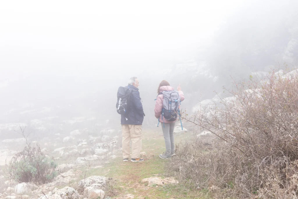 Pareja caminando en una montaña por la niebla