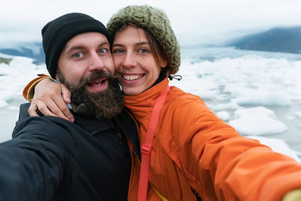 Pareja sonriente tomando un selfie en medio de glaciares